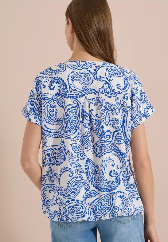 Damesblouse met blauw paisley-motief op witte ondergrond, korte mouwen, losse pasvorm.