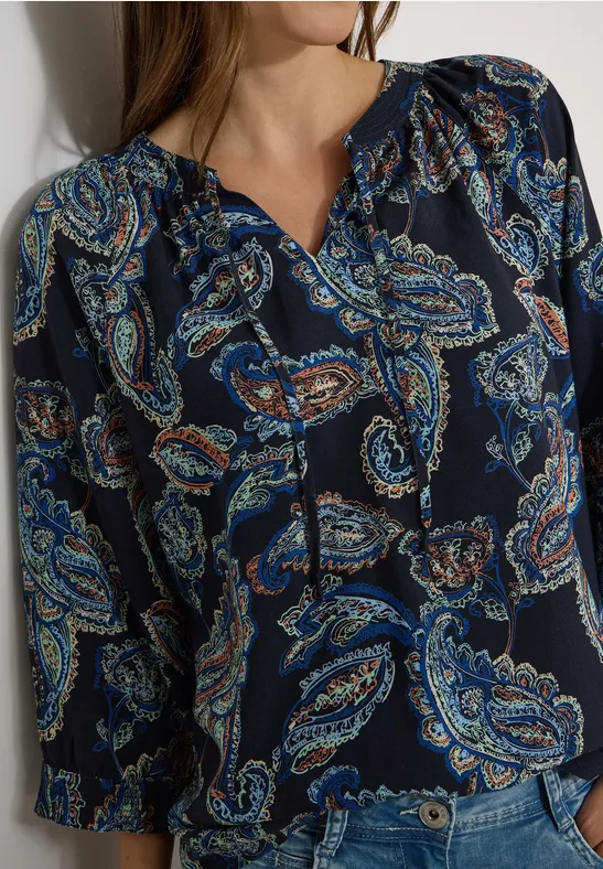 Dunkelblaue Bluse mit buntem Paisley-Muster und langen Ärmeln.