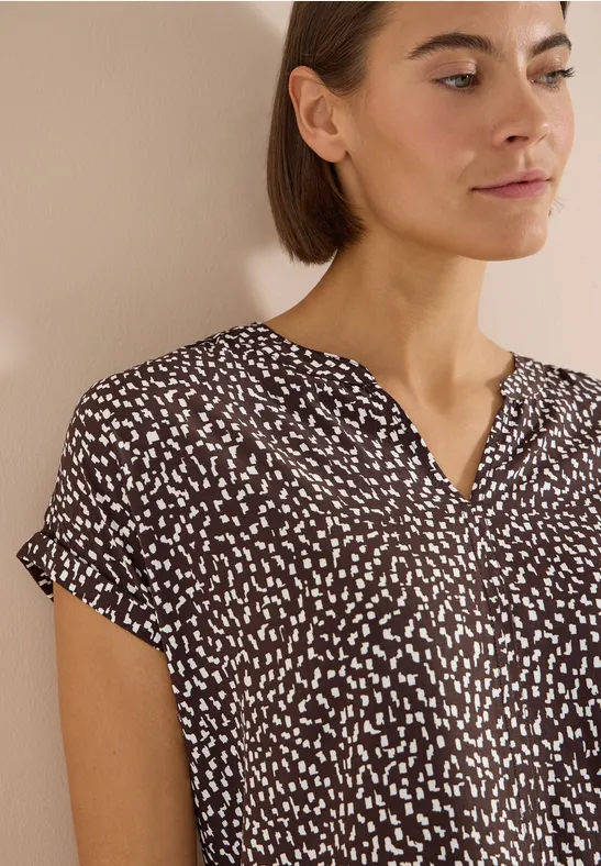Blouse femme à manches courtes marron à motifs blancs irréguliers et encolure en V.