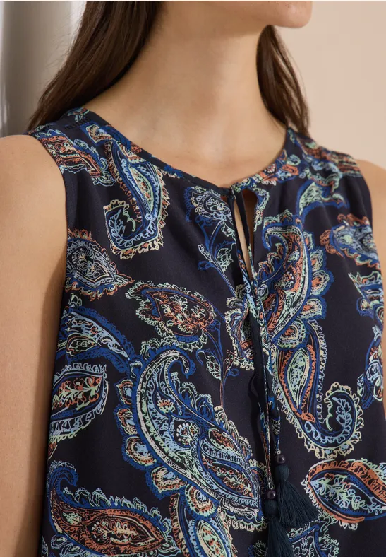 Dunkelbluse mit Paisley-Muster in Blau- und Orangetönen, ärmellos mit kleinem Schlitz am runden Ausschnitt.