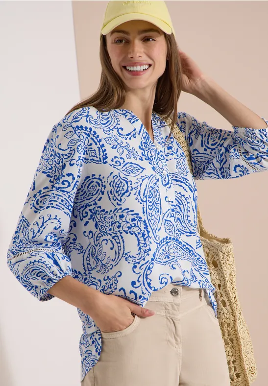 Wit overhemd met blauw paisleypatroon, beige broek, strozak en haarband