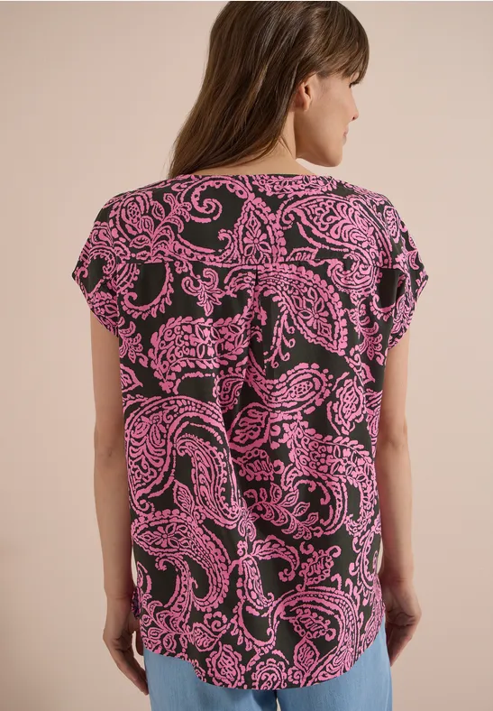 Rückansicht einer Person in kurzärmeligem Shirt mit rosa Paisley-Muster auf schwarzem Grund.