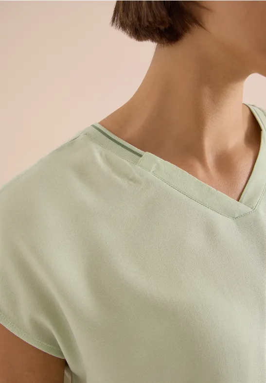 Nahaufnahme eines hellgrünen V-Ausschnitt-Shirts, das Schulter und Halsbereich zeigt.