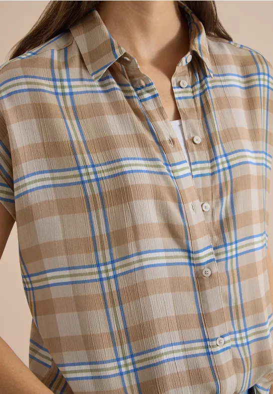 Nahe Aufnahme einer beige-karierten Kurzarmbluse mit blauen und weißen Streifen.