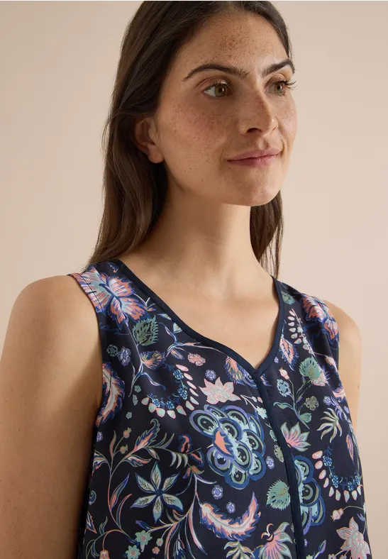 Portrait d'une femme portant un top sans manches bleu foncé à motif floral coloré