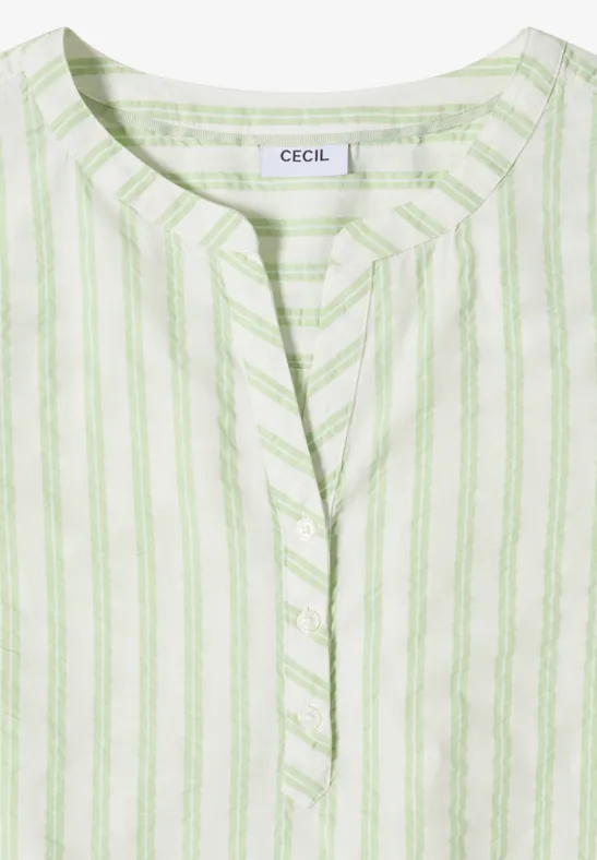 Blouse blanche légère à rayures vert pastel verticales avec encolure en V légère.