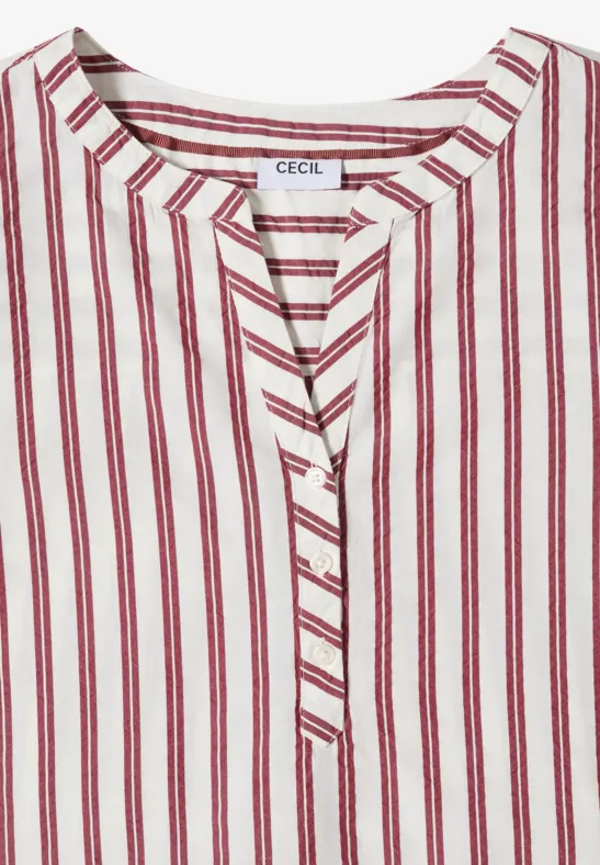 Haut blanc à rayures verticales rouges, col en V sans col classique et patte de boutonnage.
