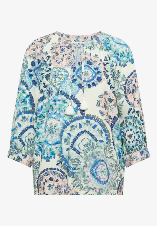 Blouse ample à manches 3/4 avec motif floral coloré dans des tons bleus et verts.