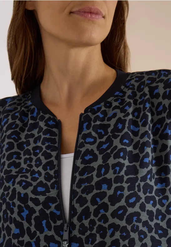 Veste femme bleu foncé à motif léopard noir, zipée, sous-pull blanc visible, gros plan.