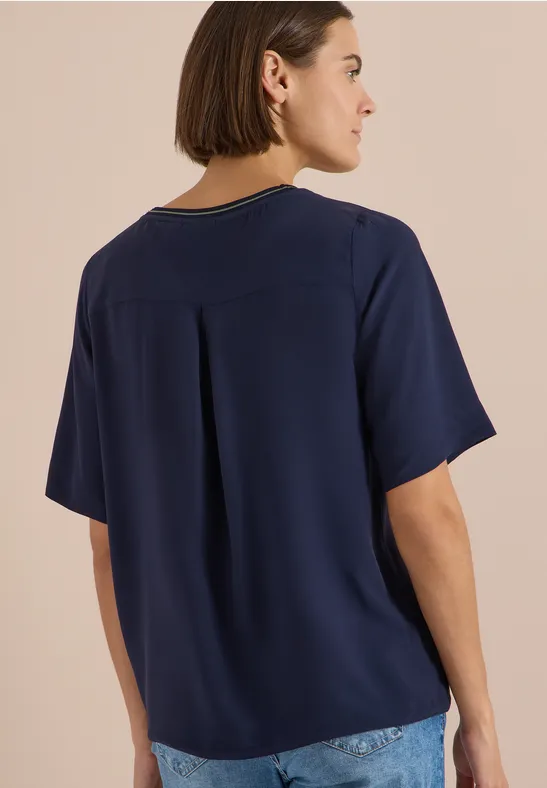 Rückansicht einer Frau in locker sitzendem, dunkelblauem T-Shirt und Jeans.