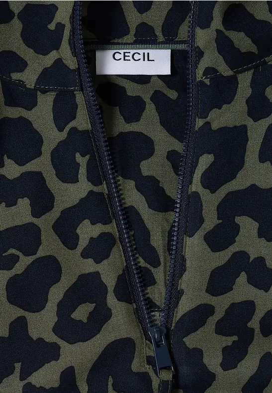 Detailaufnahme eines olivgrünen Fleckenmusters auf einem Kleidungsstück mit weißem Label 'CECIL'.