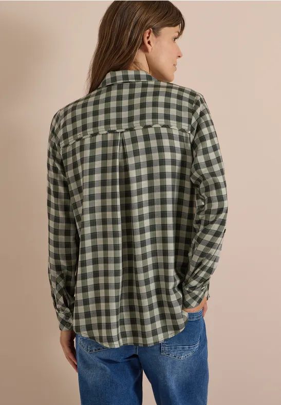 Vue arrière d’une personne portant une chemise à carreaux vert-blanc et un jean.