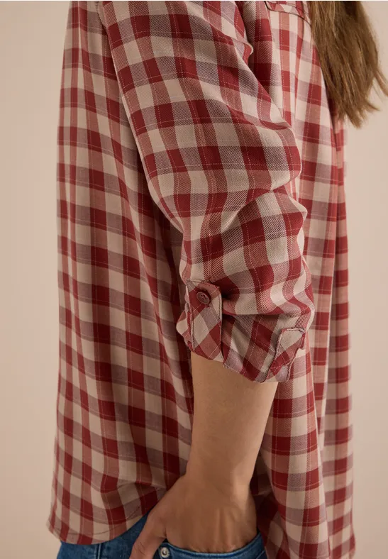 Personne porte une chemise à carreaux rouge et blanche, manches retroussées.