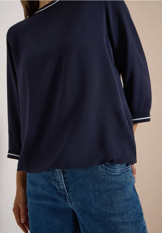 Frau trägt dunkelblauen Dreiviertelarm-Pullover mit Jeans