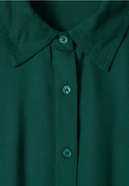 Donkergroene blouse met klassieke kraag en centrale knoopsluiting.
