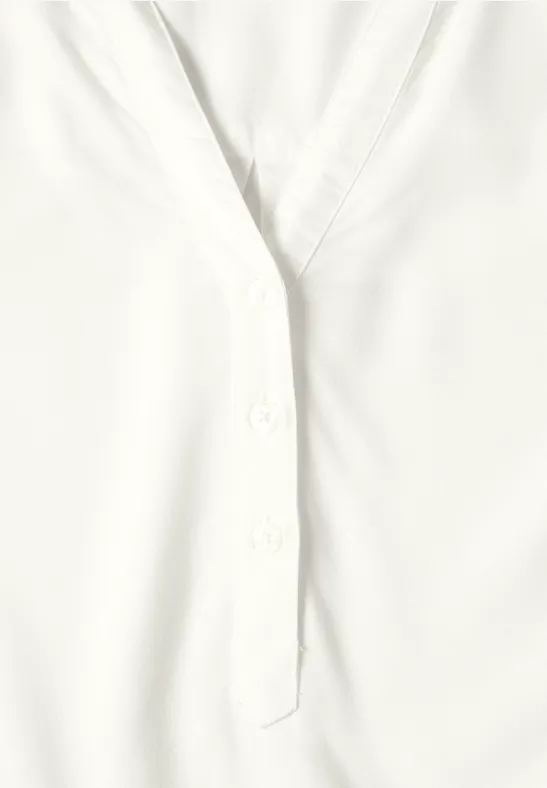 Nahaufnahme einer weißen Bluse mit Knopfleiste und V-Ausschnitt.