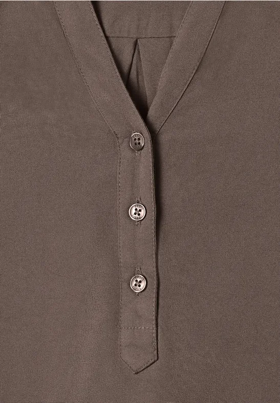 Bruin shirt met V-hals en drie knopen aan de voorkant.