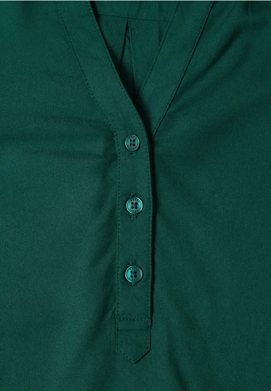 Dunkelgrünes Shirt mit V-Ausschnitt und drei Knöpfen in einer schlichten Knopfleiste.