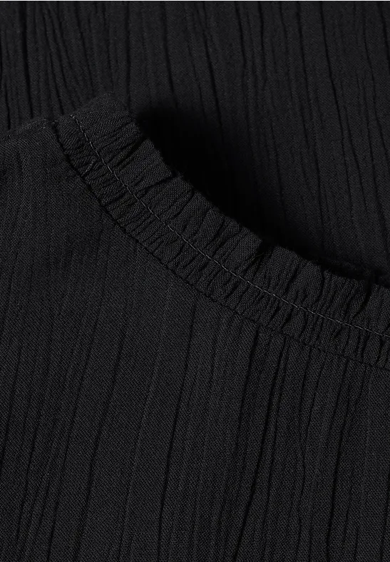 Nahaufnahme eines schwarzen, plissierten Stoffes mit elastischem Saum.