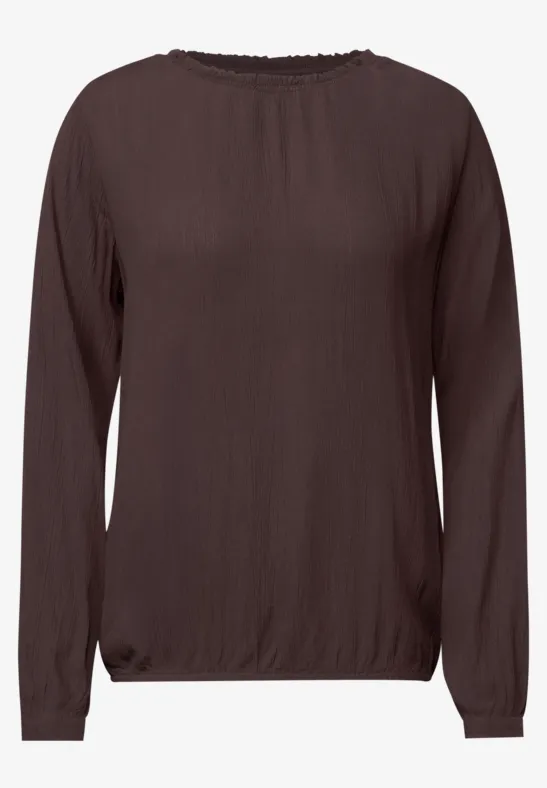 Blouse marron à manches longues et encolure ronde, coupe légèrement cintrée.
