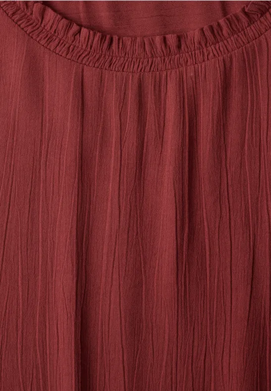 Haut en tissu rouge froncé avec encolure ronde élastique.