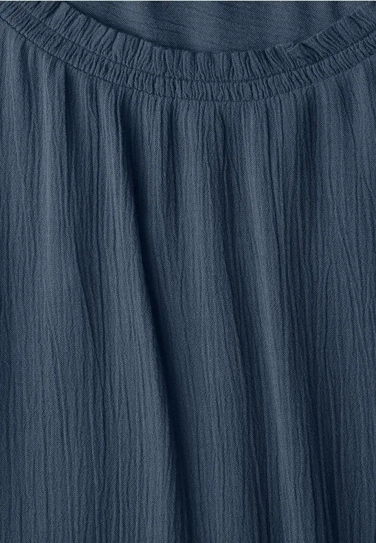 Gros plan sur un tissu bleu foncé froissé avec un col carré et un léger effet texturé.