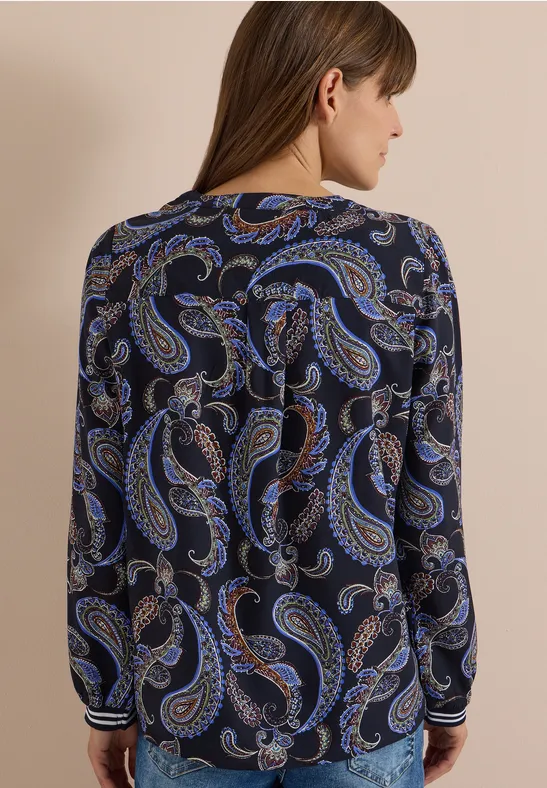 Frau von hinten in dunkelblauer Bluse mit blauem Paisley-Muster, seitliche Ansicht, schulterlanges Haar