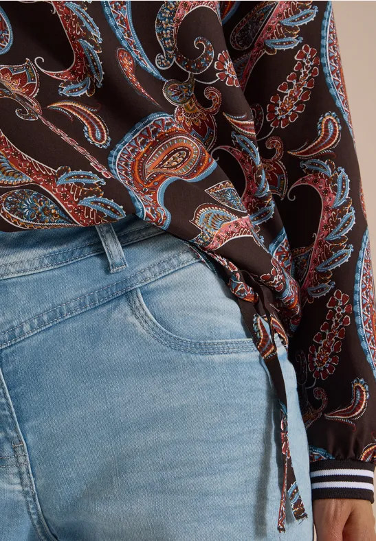 Lichtblauwe jeans en een bruin paisleyblouseje, aan de zijkant geknoopt.