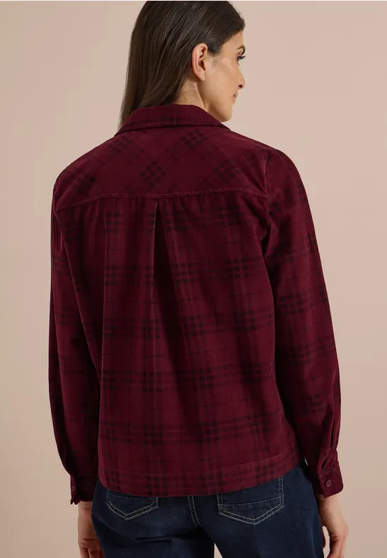 Frau von hinten in dunkelrotem kariertem Hemd und Jeans.