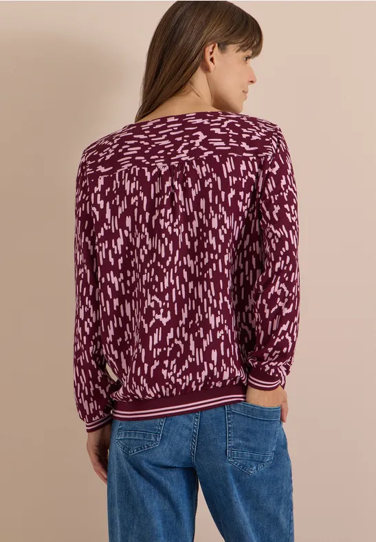 Frau von hinten in Jeans und grob gemustertem violettem Pullover