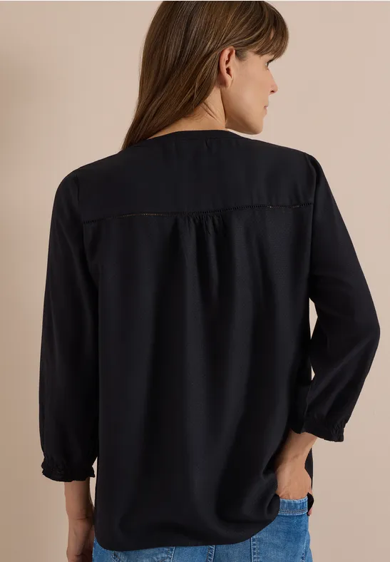 Frau von hinten in locker sitzender, langer dunkelblauer Bluse mit Gummibündchen.