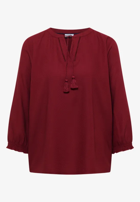 Elegante burgunderrote Bluse mit 3/4-Ärmeln und Quasten am Ausschnitt.