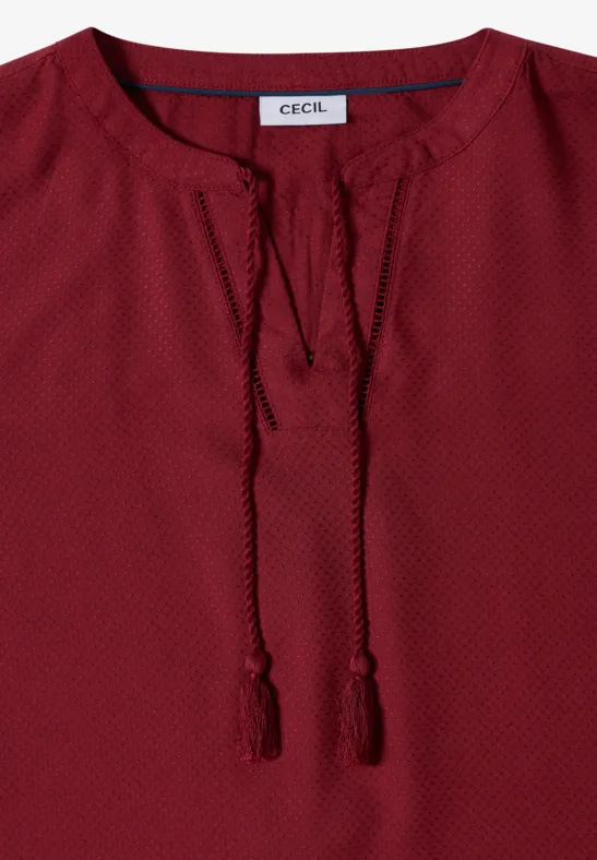 Rotes Langarm-Damenoberteil mit V-Ausschnitt, Quasten und feinem Punktmuster.