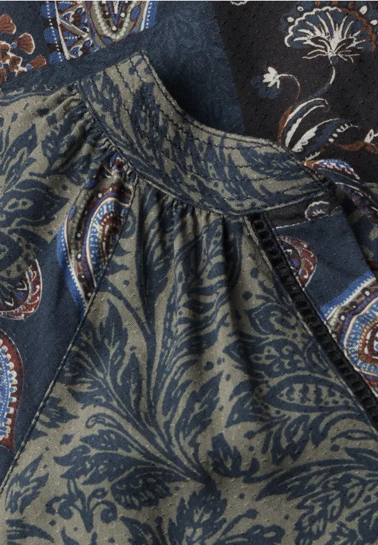 Nahaufnahme eines dunkelblauen, floral-paisley gemusterten Stoffes mit Raffung am Ausschnitt.