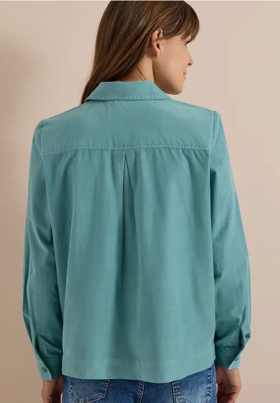 Femme de dos portant une blouse chemisier turquoise à manches longues