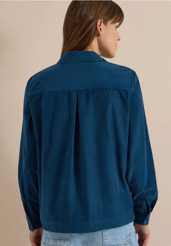 Vue de dos d'une femme portant une chemise en velours côtelé bleu foncé à manches longues.