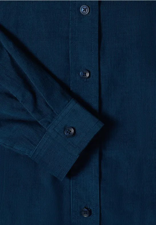 Gros plan sur une chemise bleu foncé avec patte de boutonnage et manchette.