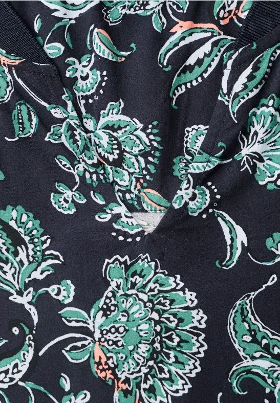 Gros plan d’un tissu noir orné de fleurs stylisées vertes et blanches.