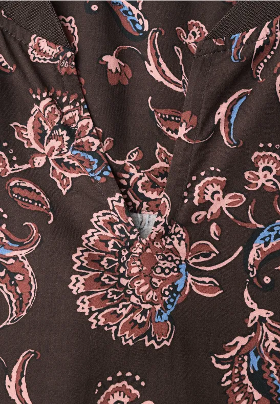 Nahaufnahme eines dunkelbraunen Blusenstoffs mit rosa-blauen Paisley- und Blumenmustern.