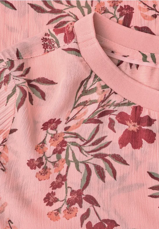 Nahaufnahme eines rosa T-Shirts mit floralem Muster.