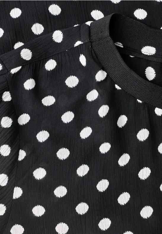 Schwarzes, geripptes Oberteil mit weißen Polka-Dots und Rundhalsausschnitt.
