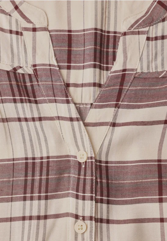 Gros plan sur une chemise à carreaux crème et bordeaux avec col en V et boutonnière centrale