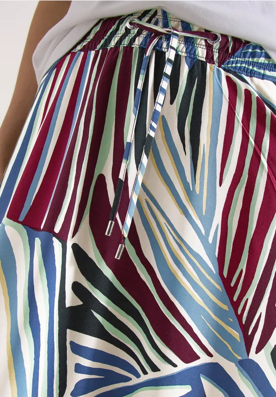 Nahaufnahme eines bunten Stoffmusters mit gestreiften, blattähnlichen Formen und verschnürtem Bund.