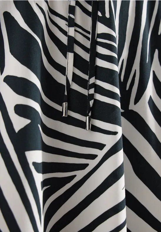 Zwart-witte stof met zebrapatroon en metalen koorduiteinden.