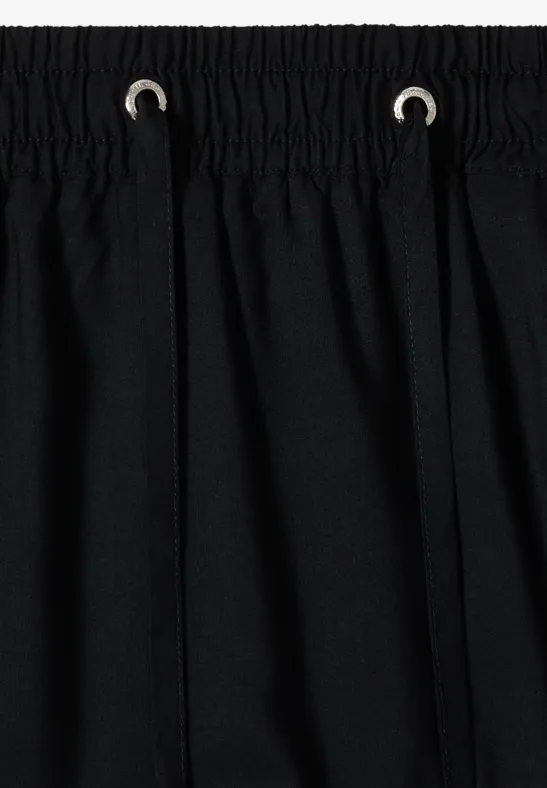 Schwarzer Stoff mit Bund und Kordelzug, einfache Nahteinfassung oben.