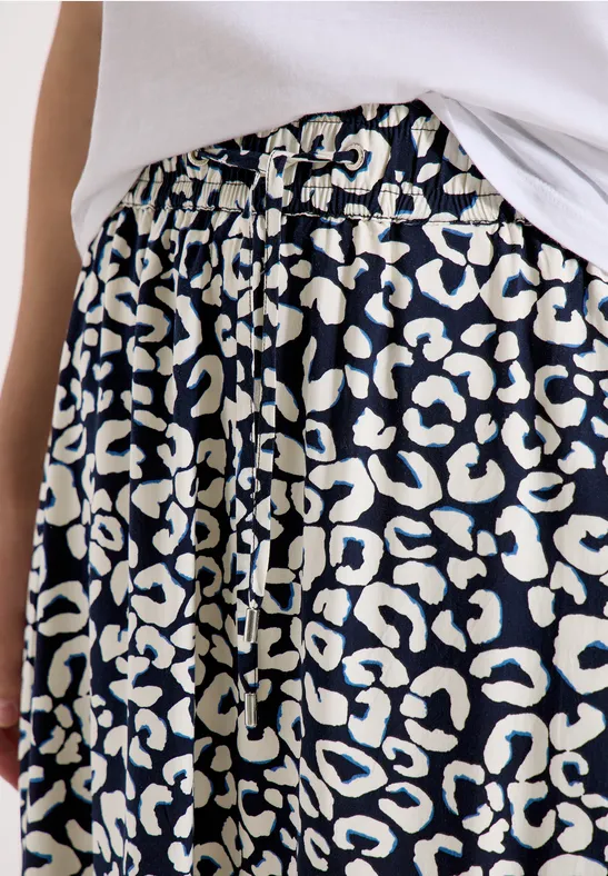 Schwarzer Rock mit weißem Leopardenmuster und Tunnelzugbund, kombiniert mit weißem Oberteil.