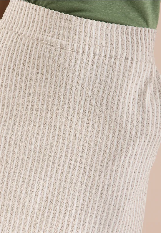 Nahaufnahme eines beigen, gerippten Strickrocks mit Tasche.