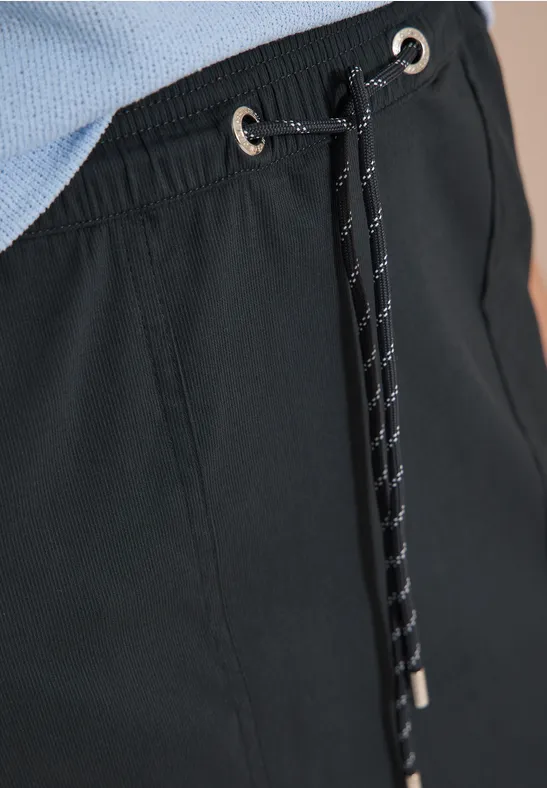 Detailaufnahme einer schwarzen Hose mit Tunnelzug, Kordel und silbernen Ösen.