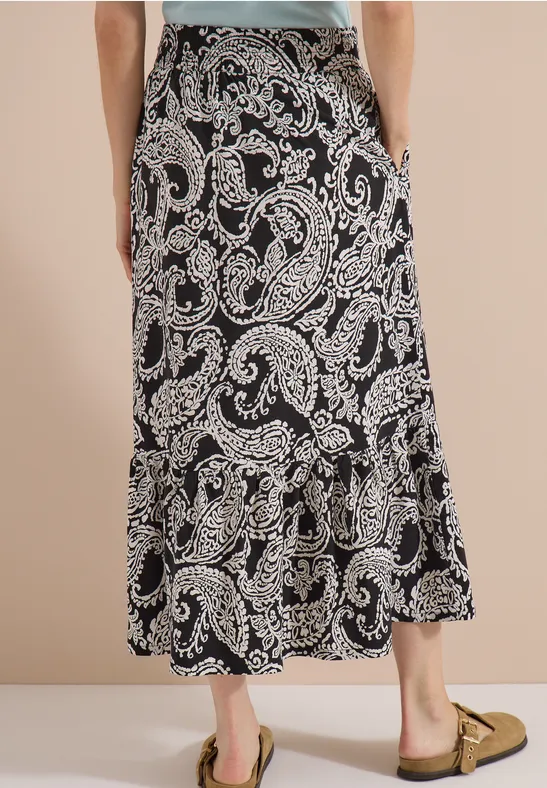 Schwarzer Maxirock mit beigem Paisley-Muster, locker fallend, hinten leicht gerafft.