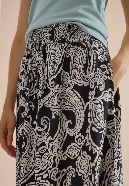 Schwarz-weißer Paisley-Midirock, kombiniert mit hellem Blusentop.